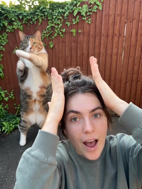 Smalltown Boy AI Dance woman raising her hands beside her head with the cat behind