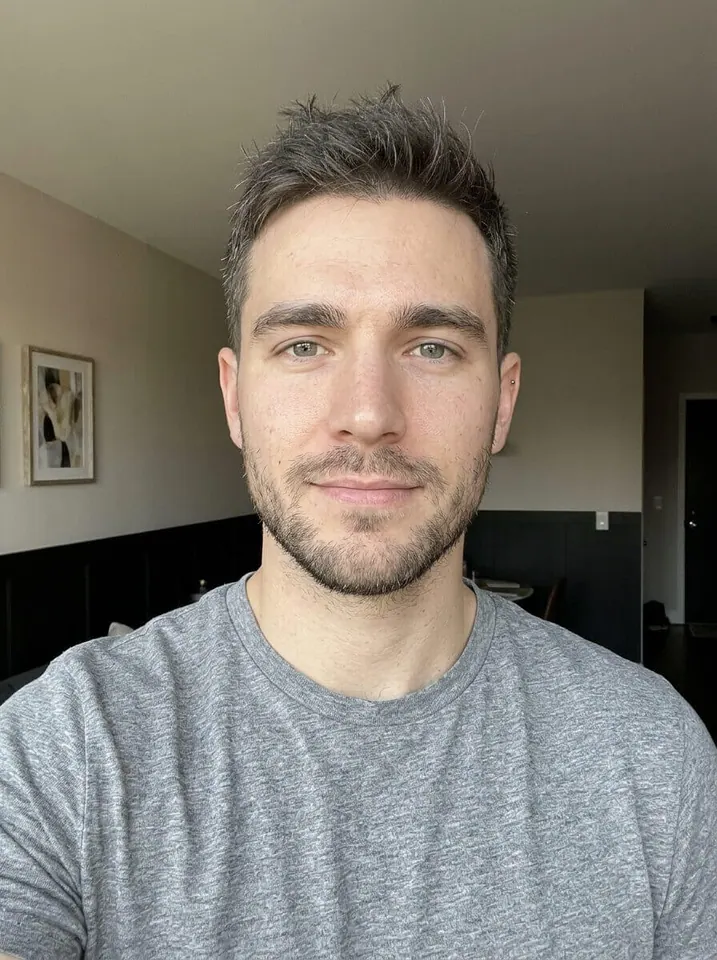 Man in a gray T-shirt taking an indoor selfie